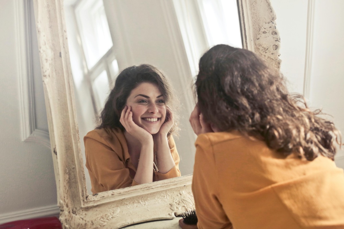 Happy woman looking at her reflection in the mirror