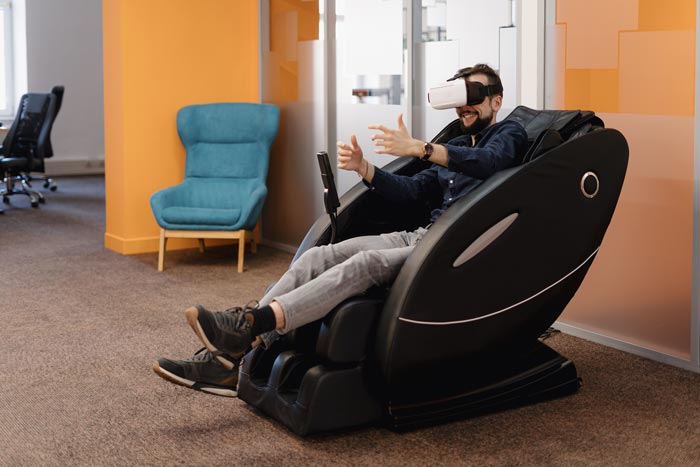 Guy wearing VR glasses while relaxing in office massage chair