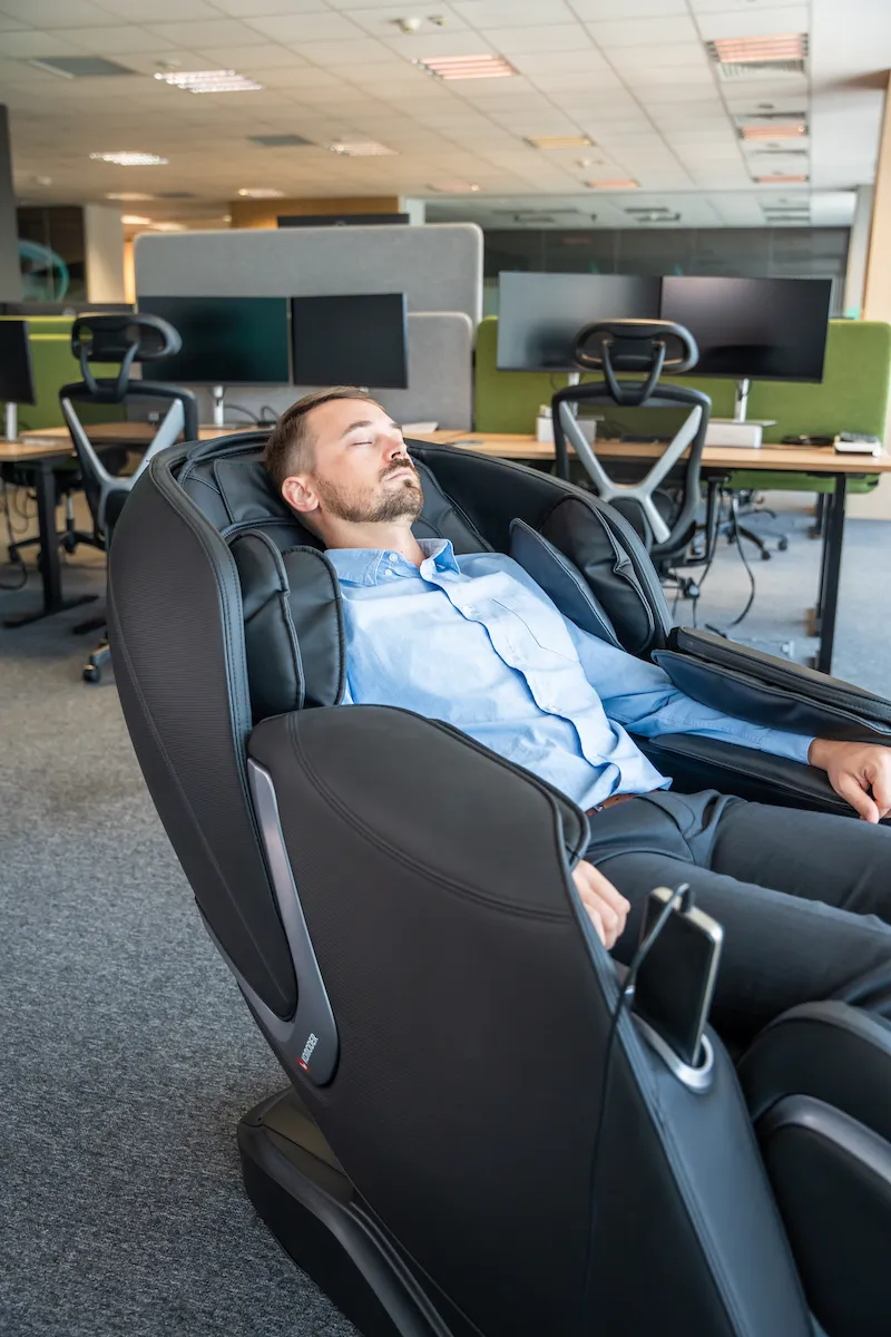 Angajat care se relaxeaza la birou printr-un masaj in fotoliul electric Komoder Corporate